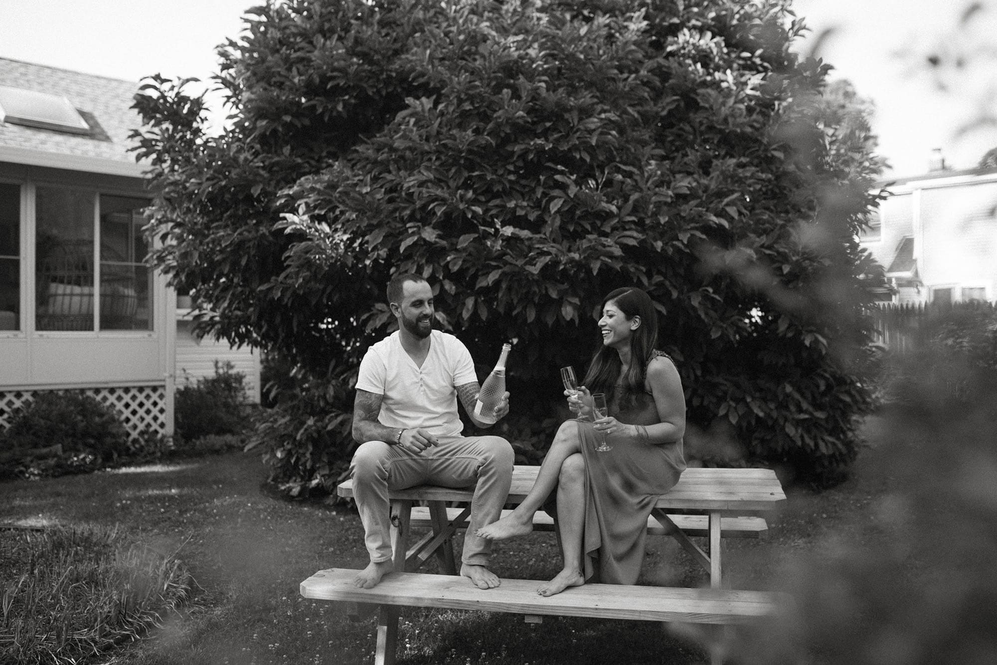couple drinking wine at a picnic table engagement photoshoot black and white