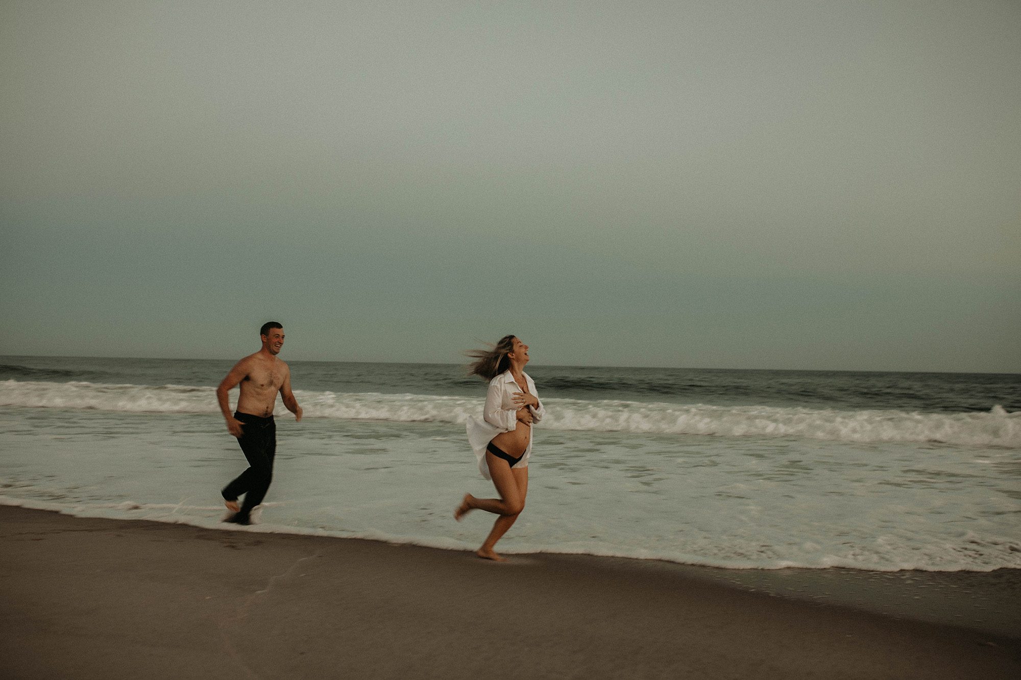 Couple running along the shore on the beach.