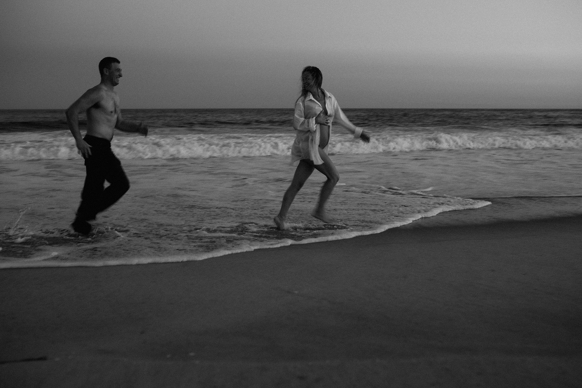 Couple running along the shore on the beach.