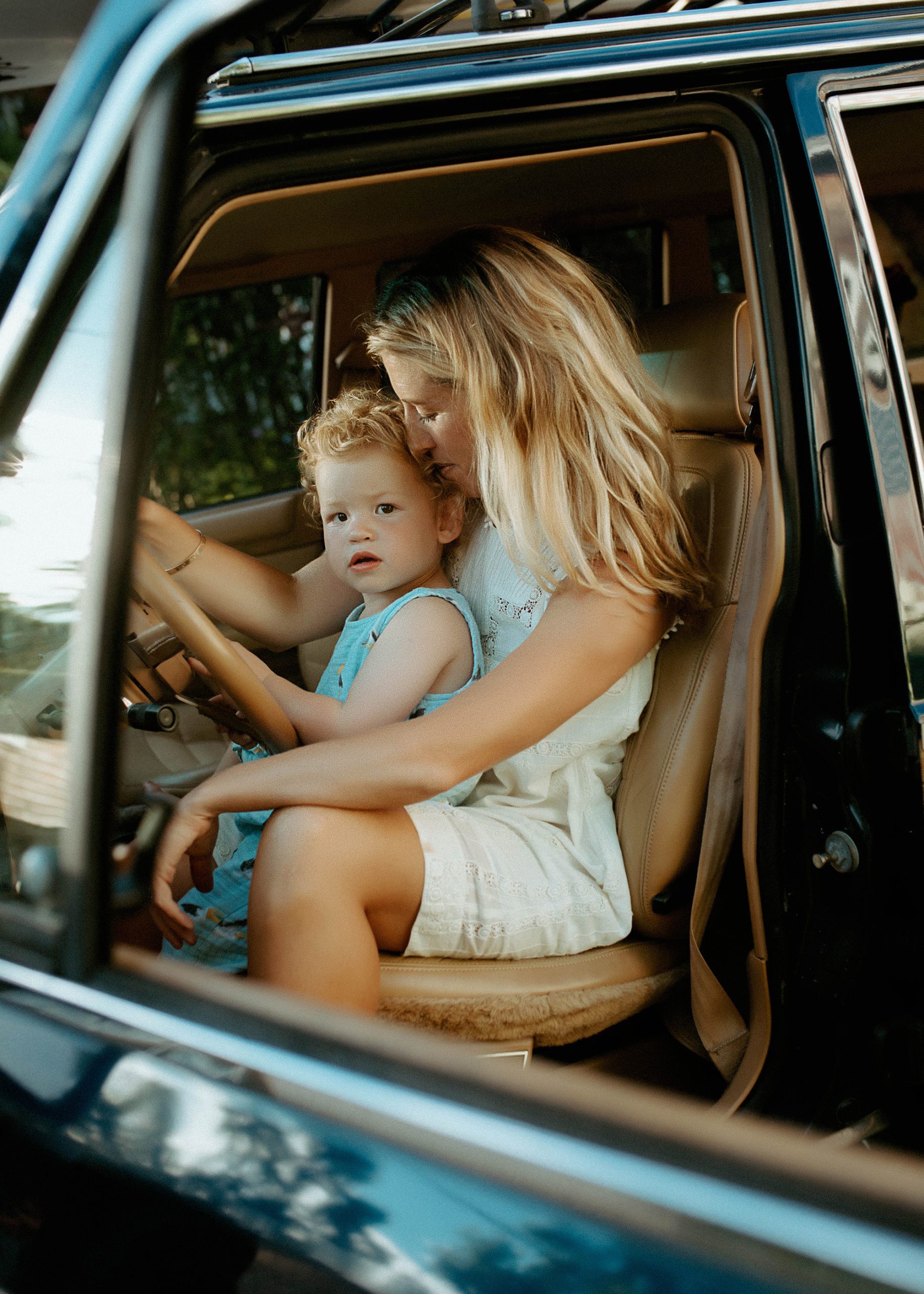 New England mom and baby family portraits in the front seat of their wood paneled jeep wagoneer with a surfboard on top in the summertime, Long Island family photographer