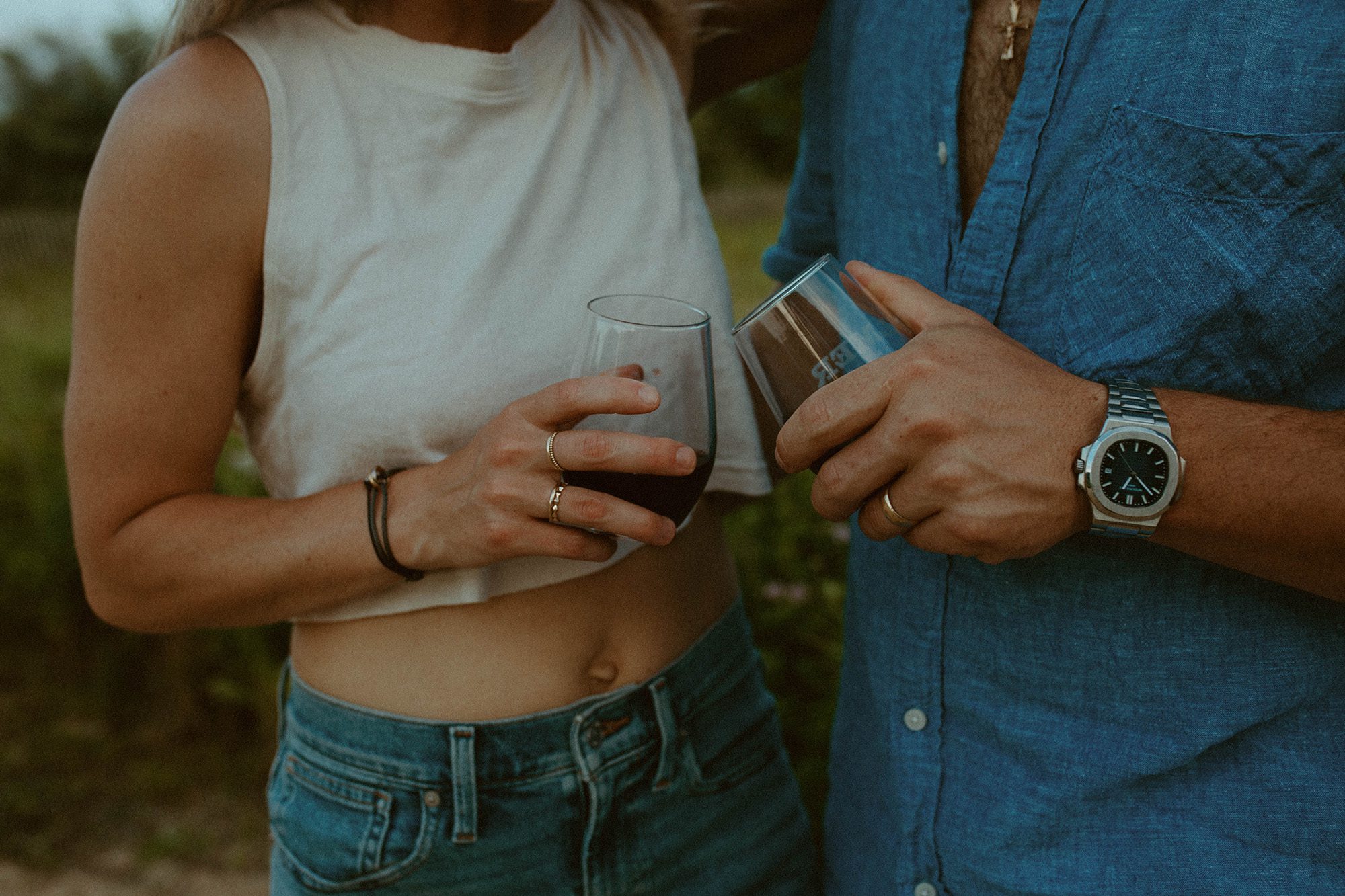 couples photoshoot on the beach, husband and wife poses in denim and white outfits with wine