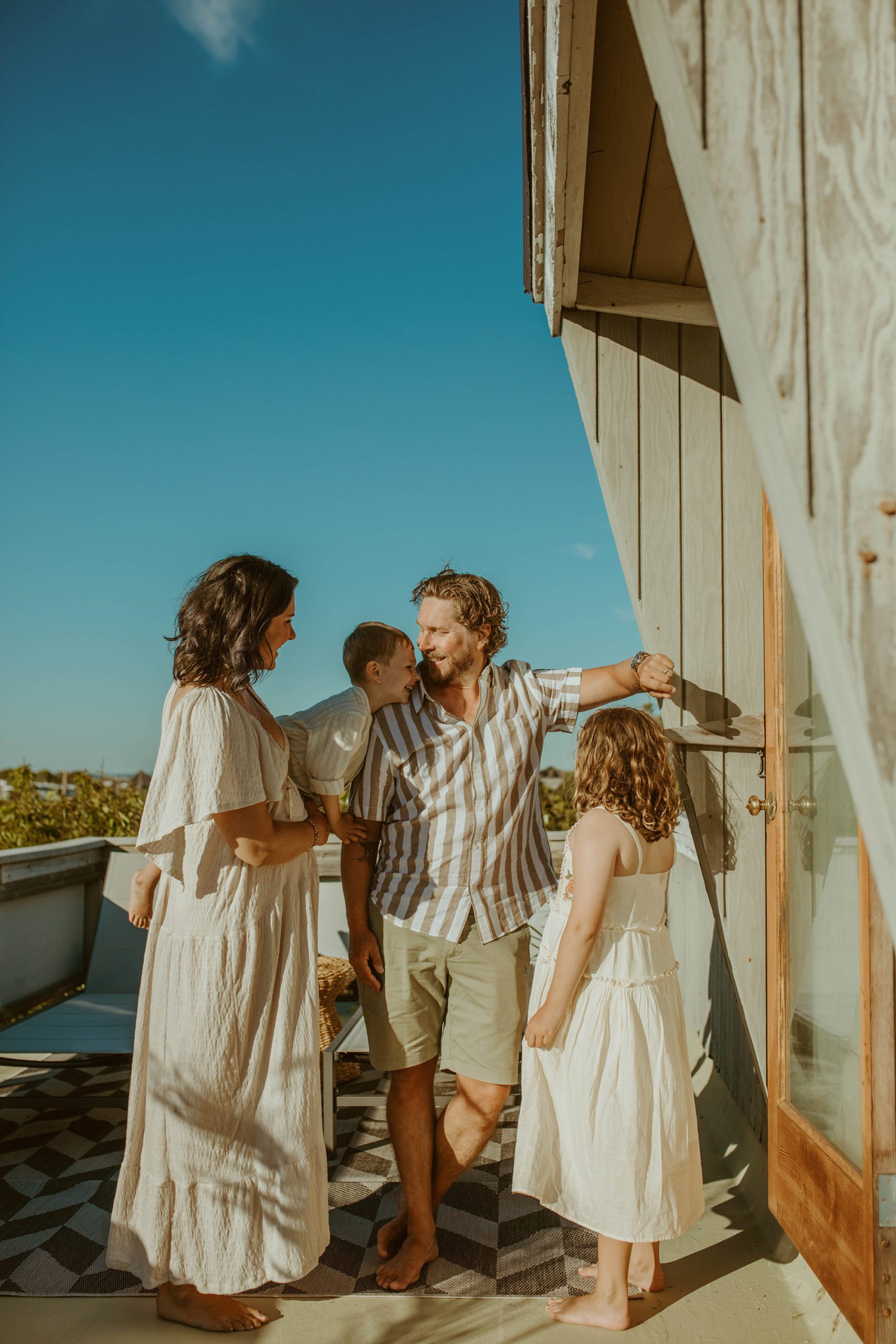 beach family portraits. family of 4 poses in front of their modern fire island beach house. 