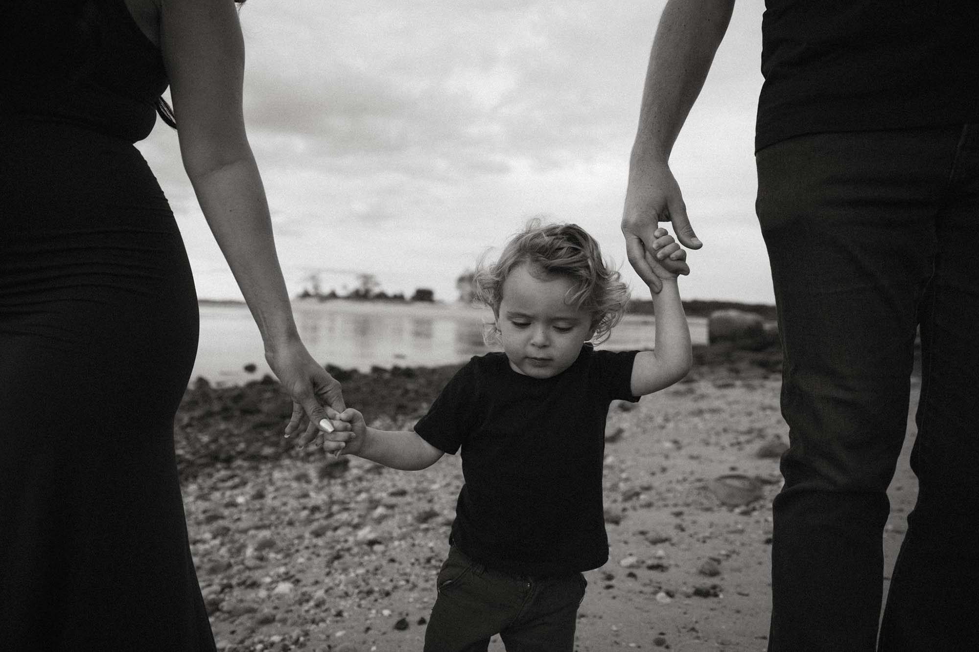 black and white family photos beach portrait son holding hands with parents