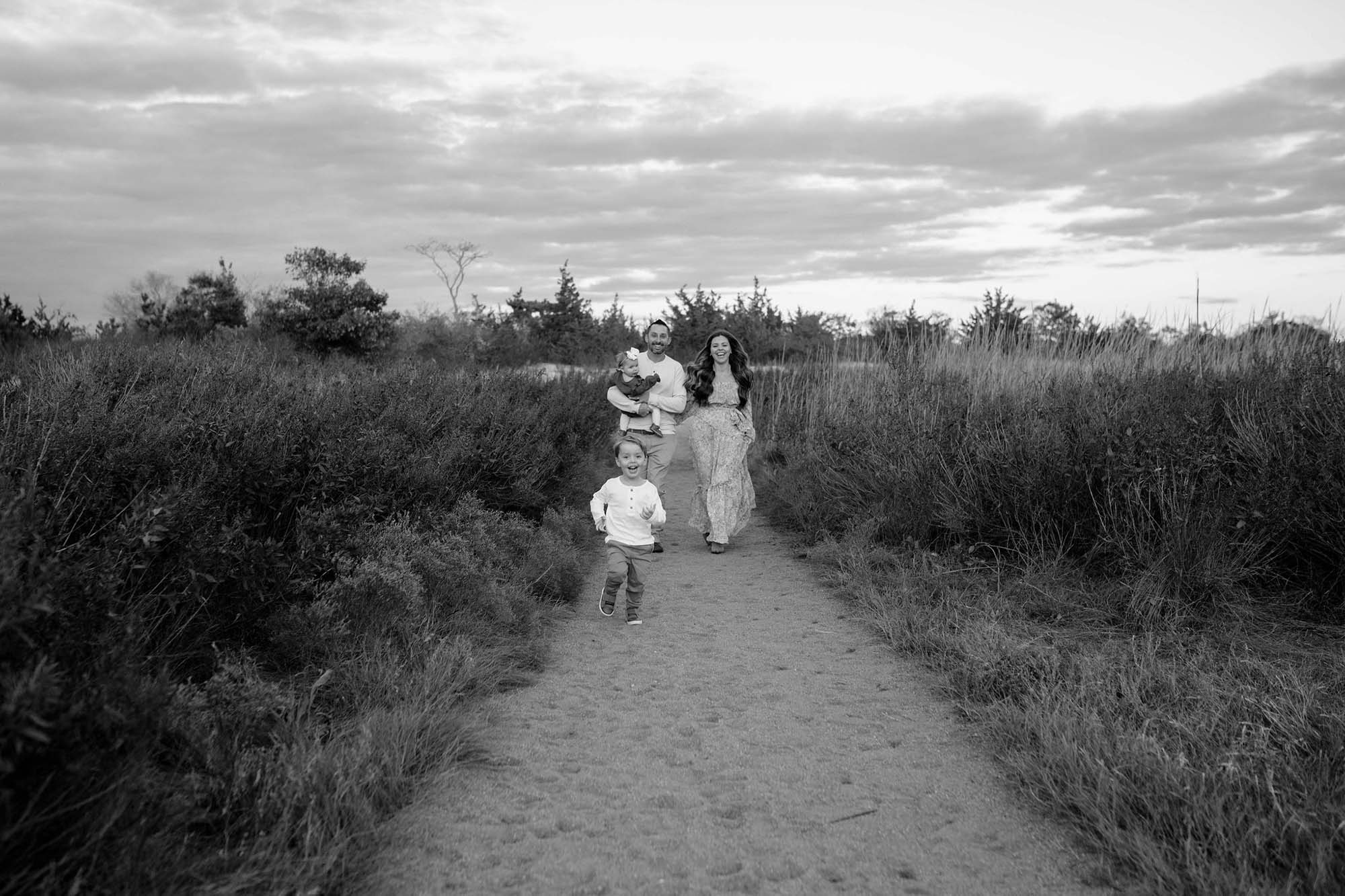 black and white family of four running on the beach,  beach family portraits, Long Island family photographer