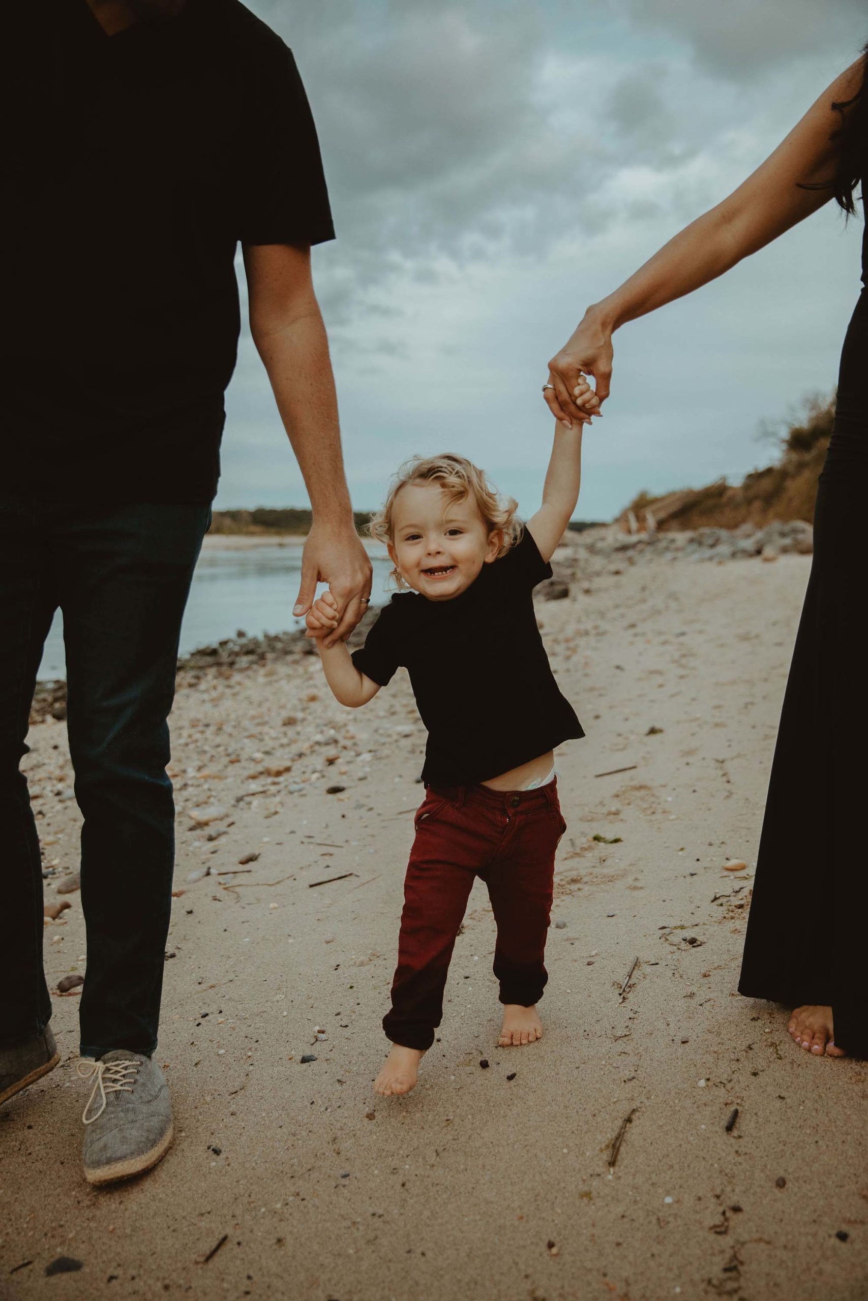 son holding parents hands beach family photos 